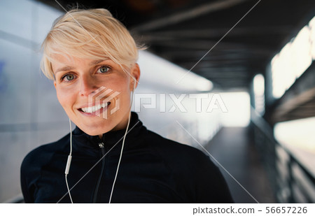 A portrait of young sportswoman doing exercise outdoors, resting. A portrait of young sportswoman doing exercise outdoors, resting. 56657226