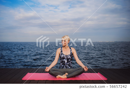 A portrait of young sportswoman doing yoga exercise on beach. Copy space. A portrait of young sportswoman doing yoga exercise on beach. Copy space. 56657242