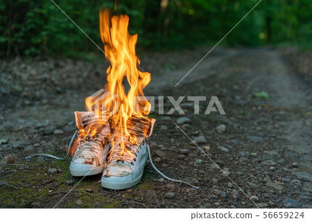 Used white high sneakers burning on a rural road Used white high sneakers burning on a rural road 56659224