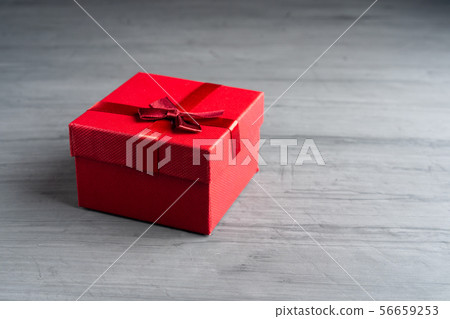 Red square holiday gift box against a dark 56659253
