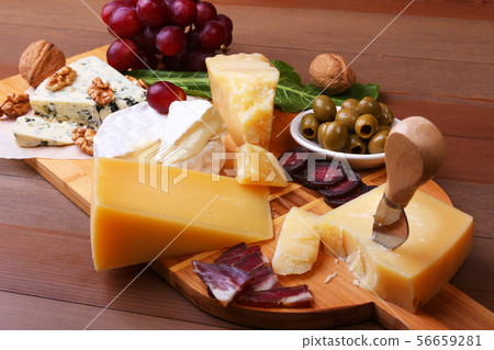 Assortment of cheese with fruits, grapes, nuts and cheese knife on a wooden serving tray. 56659281