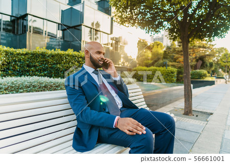 Indian businessman holding mobile phone wearing blue suit 56661001