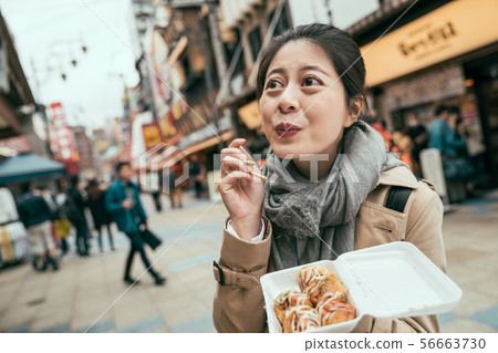 asian woman eat takoyaki with lovely smile 56663730