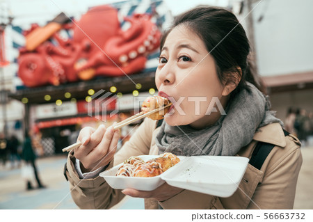 female traveler eating dumpling batter on street 56663732