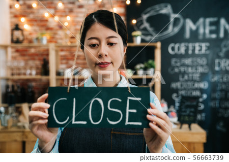 Closed sign board in woman hands hanging window 56663739