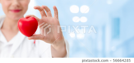 Doctor holding a red heart at hospital office. 56664285