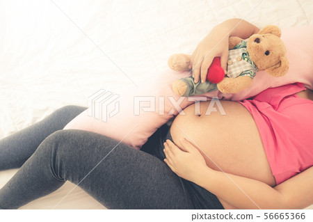 Happy pregnant woman sleeping on bed in bedroom. Happy pregnant woman sleeping on bed in bedroom. 56665366