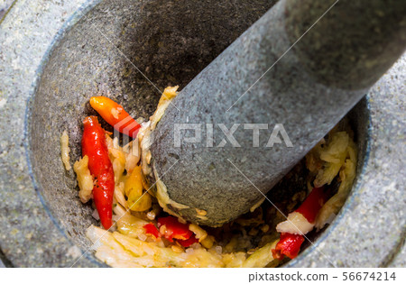 Pepper and garlic pounded in a stone mortar 56674214