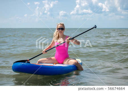 Young athletic woman in bright pink swimsuit doing 56674664
