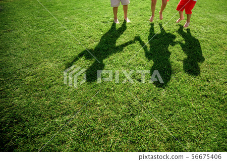 Kids with their shadows on grass.  56675406