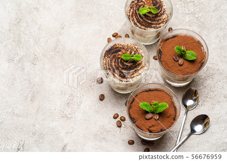 Classic tiramisu dessert in a glass cup on concrete background Classic tiramisu dessert in a glass cup on concrete background 56676959