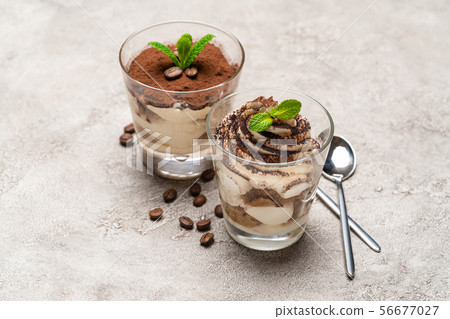 Classic tiramisu dessert in a glass cup on concrete background Classic tiramisu dessert in a glass cup on concrete background 56677027