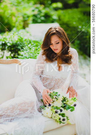 Close-up portrait of young beautiful bride in white negligee with bridal bouquet Close-up portrait of young beautiful bride in white negligee with bridal bouquet 56680790