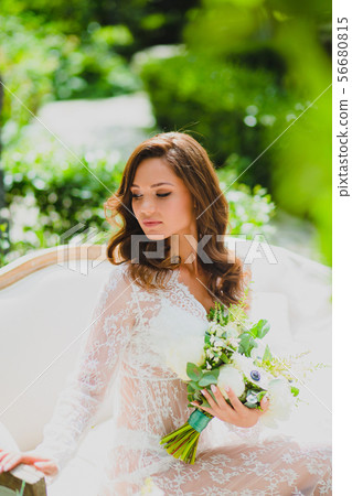 Close-up portrait of young beautiful bride in white negligee with bridal bouquet Close-up portrait of young beautiful bride in white negligee with bridal bouquet 56680815