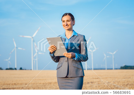 Investor in wind turbines with computer evaluating her investment on site 56683691