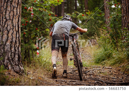 dirty and tired cyclist walking uphill dirty and tired cyclist walking uphill 56683750