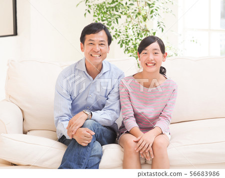 微笑的父親和女兒坐沙發 微笑的父親和女兒坐沙發 56683986
