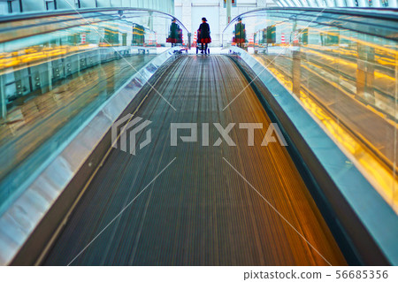Woman pushing a moving walkway and stroller Woman pushing a moving walkway and stroller 56685356
