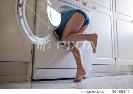 Child is hiding into the washing machine 56686345