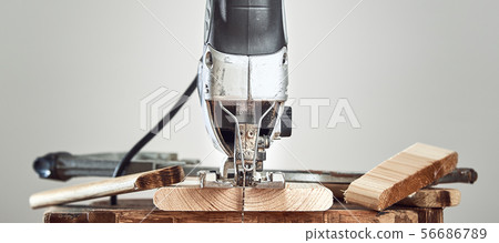 Electric jigsaw closeup on a Board on a gray background. Front view. 56686789