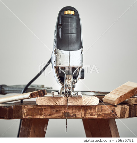 Electric jigsaw closeup on a Board on a gray background. Front view. 56686791