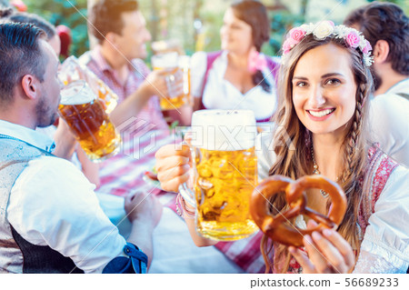 Woman toasting to the camera with glass of beer in Bavarian pub 56689233