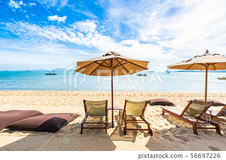 Beautiful tropical beach sea and ocean with coconut palm tree and umbrella and chair on blue sky and white cloud Beautiful tropical beach sea and ocean with coconut palm tree and umbrella and chair on blue sky and white cloud 56697226