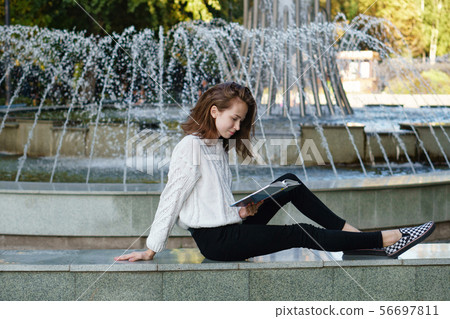 Student reads book at fountain 56697811