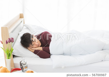 Asian man lie on one's side on the bed.. 56700987