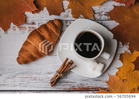 Autumn morning Breakfast with a Cup of coffee and a croissant on a wooden table with maple leaves Autumn morning Breakfast with a Cup of coffee and a croissant on a wooden table with maple leaves 56705694