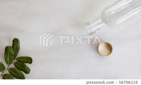 Flat lay of a long empty glass bottle and leaves. Flat lay of a long empty glass bottle and leaves. 56706228