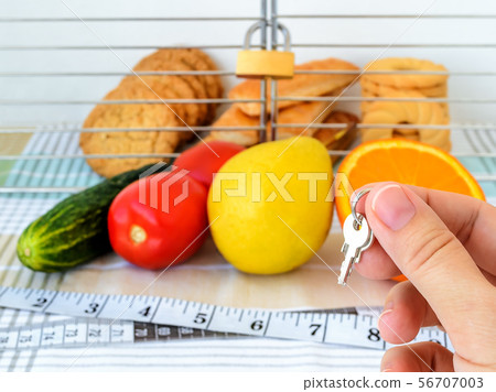 Woman hand holds the key of cage with cookies. 56707003