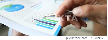 Male hand hold silver pen with chart aganist 56709473