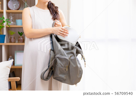 Pregnant woman putting a pouch in the backpack Pregnant woman putting a pouch in the backpack 56709540