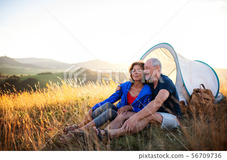 Senior tourist couple in love sitting in nature at sunset, resting. 56709736