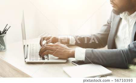 African american businessman typing on laptop filling financial reports 56710393
