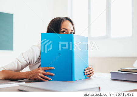 Lovely girl student hiding behind the book 56712451