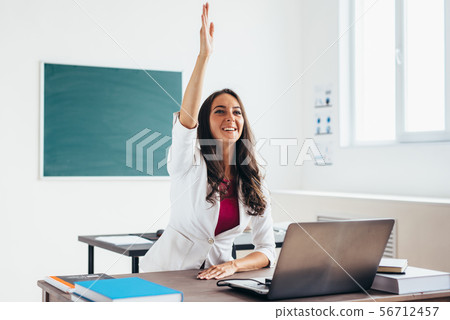 Woman raises hand sitting at the desk like a pupil. Woman raises hand sitting at the desk like a pupil. 56712457