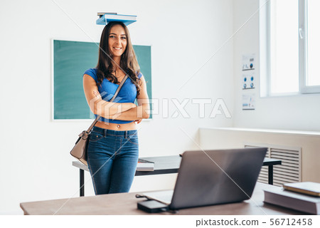 Portrait of female student holding book on her head 56712458