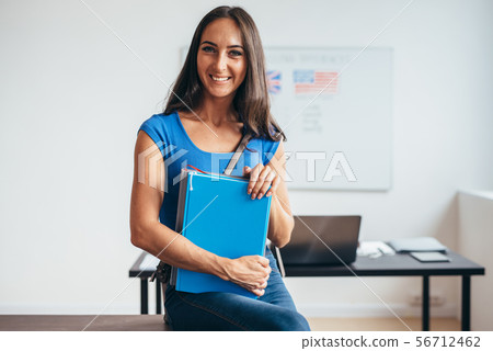 Female student sitting at table smiling and looking at camera. 56712462