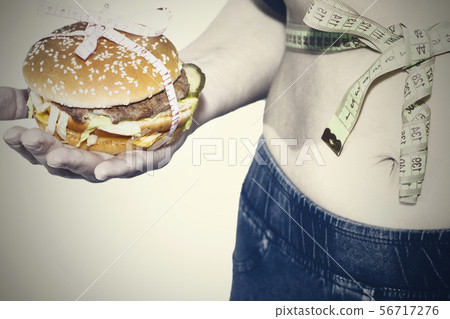 Burger cheeseburger in hands with measure tape 56717276