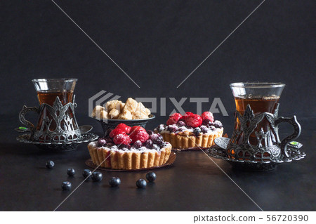 Tea cups, tarts cakes sweets on black  background 56720390