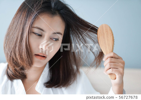 Woman hand holding comb with serious hair loss 56727678