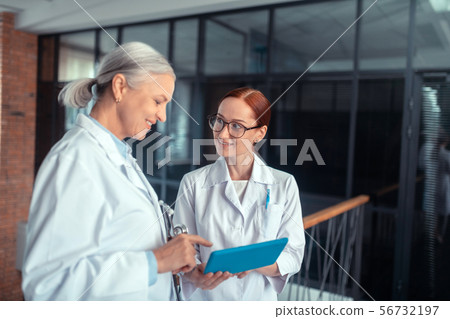Smiling senior female doctor standing in the corridor 56732197