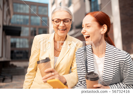 Businesswomen standing outdoors with paper cups of coffee 56732416