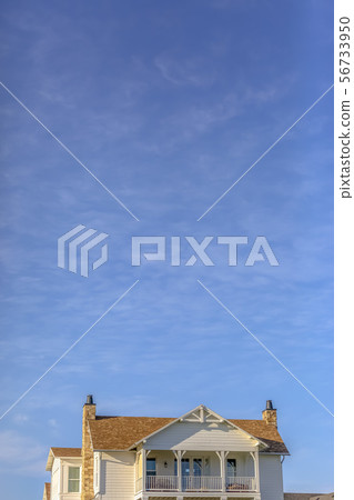 Upper storey of home againt sky with wispy clouds Upper storey of home againt sky with wispy clouds 56733950