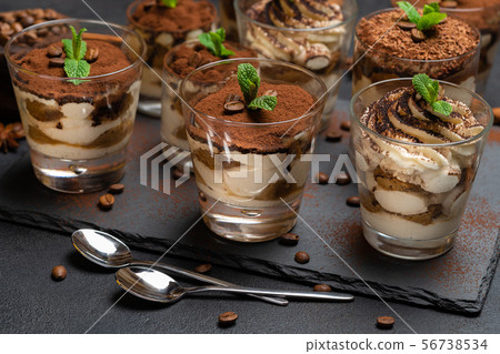 Group of portions of Classic tiramisu dessert in a glass cup on stone board on concrete background Group of portions of Classic tiramisu dessert in a glass cup on stone board on concrete background 56738534
