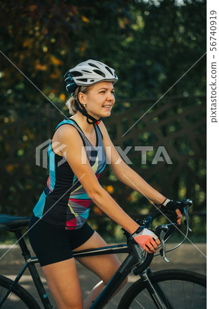 Photo on side of young woman in helmet on bike ride on summer day 56740919