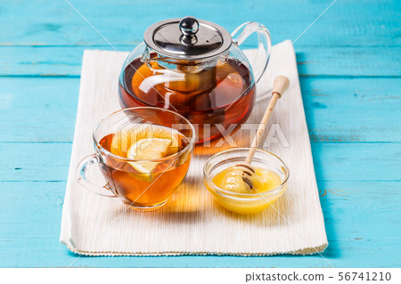 Glass cup of tea with lemon, glass teapot and honey. Glass cup of tea with lemon, glass teapot and honey. 56741210