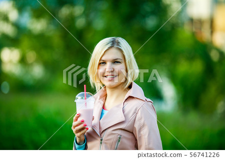 Woman in park with milkshake 56741226